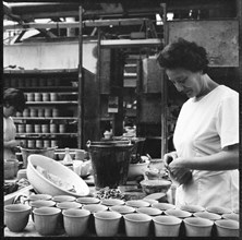 Woman fixing handles to mugs prior to firing in a pottery works, Stoke-on-Trent, 1965-1968