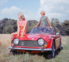 1968 Triumph TR5 with female models, (copyright B.M.I.H.T.). Creator: Unknown.