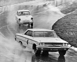 Ford Galaxie, J.Sears, leads Ford Anglia in wet at Brands Hatch 1963. Creator: Unknown.
