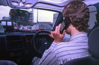 Man driving whilst using built-in car telephone 1990. Creator: Unknown.