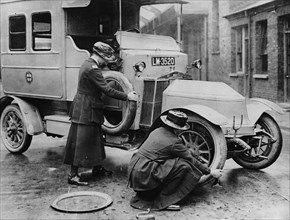 Siddeley Deasy ambulance 1911, women changing wheel. Creator: Unknown.