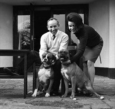 John Surtees relaxes at home with his wife and pet dogs in 1966. Creator: Unknown.