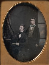 Two Young Men in Bow Ties, One Seated Holding a Book, One Standing, 1850s.