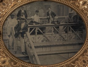 Group of Men and Boys Standing Along the Railing of the Fulton Street Bridge, 1866-68.