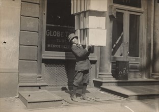 Wagon boy or "tail boy" helping to load the wagon, c. 1914.