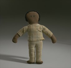 A male cloth doll with tan clothing. The doll has a tan shirt with stripes on it and pants.