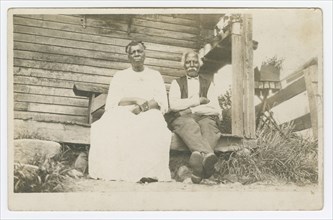 Photographic postcard of an elderly couple sitting on a porch, 1904-1929. Creator: Unknown.