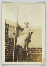 Photographic print of a woman on a brick wall, early 20th century. Creator: Unknown.