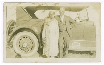 Photograph of a man and woman in front of car, ca. 1921. Creator: Unknown.