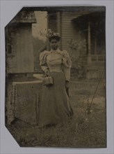 Tintype of a woman wearing a dress with hat and bag, 1890s. Creator: Unknown.