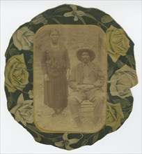 Photographic portrait of a man and woman on floral paper backing, early 20th century. Creator: Unknown.