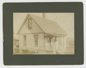 Photograph of a woman standing on the porch of a house, early 20th century. Creator: Unknown.