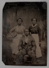 Untitled (Portrait of Two Standing Women and One Seated Man), 1880. Creator: Unknown.