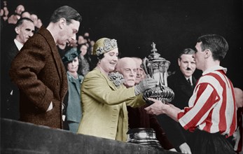 'The Queen Presents The Cup', 1937. From "The Sphere - Coronation Record Number". [The Sphere, London, 1937]. (Colorised black and white print).