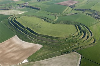 Maiden Castle, known primarily as an Iron Age multivallate hillfort earthwork, but also contains a Neolithic causewayed enclosure earthwork and long mound earthwork, and the remains of a Roman temple,...