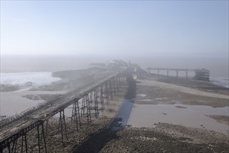 Birnbeck Pier, Birnbeck Island, Weston-Super-Mare, Somerset, 2018. General view of the derelict pier shrouded in mist at low tide, from the east.
