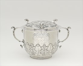 Two-Handled Covered Cup, 1698/1720. Silver cup with lid, two handles with leaf designs, used to serve syllabub, a sweetened or flavoured wine, cider, beer, or ale into which milk was whipped. Scroll-l...