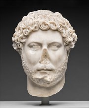 Portrait Head of Emperor Hadrian, 130-138. The white head of a man with a blank expression, a missing nose that has broken off, low cheekbones, curly hair, and a close-cut wavy beard.