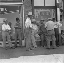 Drought farmers line the shady side of the main street of the town, Sallisaw, Oklahoma, 1936. Creator: Dorothea Lange.