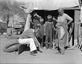 Tom Collins, manager of Kern migrant camp talking with drought refugee and her..., CA, 1936. Creator: Dorothea Lange.
