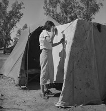 Woman in a California pea pickers' camp, mending the tent, 1937. Creator: Dorothea Lange.