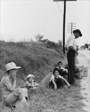 A hitchhiking family waiting along the highway in Macon, Georgia, 1937. Creator: Dorothea Lange.