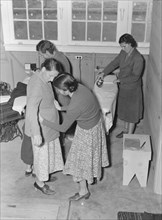 Camper receives help in fitting a coat from WPA sewing instructor, FSA, California, 1938. Creator: Dorothea Lange.