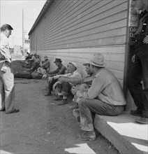 Possibly: Idle men seated in shade on the other side..., Tulelake, Siskiyou County, California, 1939 Creator: Dorothea Lange.