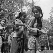 Girls adjusting each others' packs for a hike at Camp Fern Rock, Bear Mountain, New York, 1943. Creator: Gordon Parks.