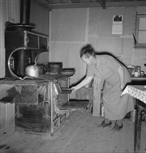 Mrs. Wardlow baking corn bread in her dugout basement home. Dead Ox Flat, Malheur County, Oregon.