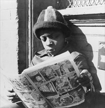 Washington, D.C. Negro youth reading a funny paper on a door step in the Southwest section.