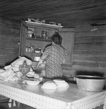 Wife of tobacco sharecropper putting breakfast dishes away. Person County, North Carolina.