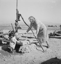 Mrs. Soper with youngest child at the well. Willow creek area, Malheur County, Oregon.