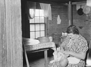 Wife of tobacco sharecropper bathing baby in kitchen. Person County, North Carolina.