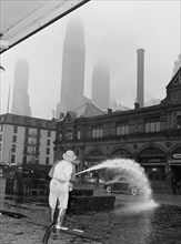 City sanitation workman washing streets at Fulton fish market. New York, New York.