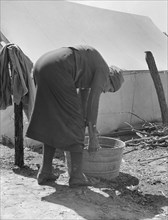 A grandmother washing clothes in a migrant camp. Stanislaus County, California.