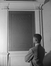Washington, D.C. Student reading bronze plaque in library of Howard University.