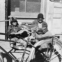 Washington, D.C. Two Negro boys reading the funnies on a doorstep.