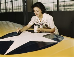 Painting the American insignia on airplane wings is a job...Air Base, Corpus Christi, Texas, 1942. Creator: Howard Hollem.
