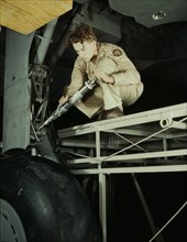 A hydraulic mechanic greasing the landing gear of a transport..., Fort Worth, Texas, 1942. Creator: Howard Hollem.
