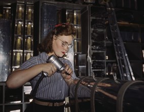 Operating a hand drill at the North American Aviation, Inc., a woman is in the control..., 1942. Creator: Alfred T Palmer.