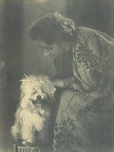 Seated woman petting her white dog, c1900.