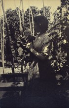 Woman holding an infant outdoors, between 1920 and 1940.
