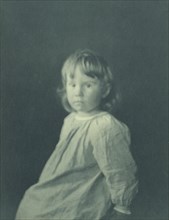Seated girl with body facing left looking at the camera, c1900.