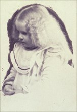 Young fair haired girl seated with hands in her lap, c1900.