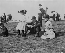 Parents and children seated on grass at state fair, St. Paul, Minnesota, 1900?.