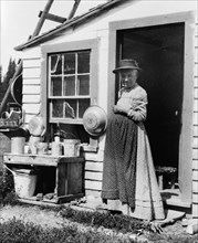Elderly woman, standing at doorway, on Mackinac Island, Michigan, 1903.