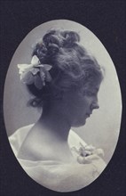 Oval portrait of woman with a flower in her hair and a corsage on her dress, c1900.