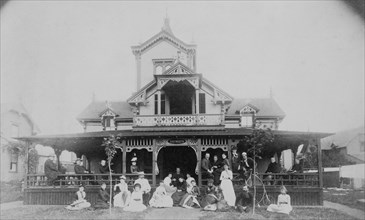Frances Benjamin Johnston and family on porch and in front of house, between 1890 and 1910.