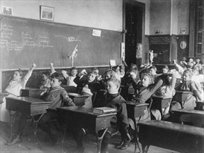 Children seated at desks in Washington, D.C. classroom, stretching, (1899?).